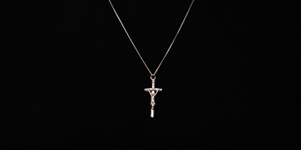 Silver crucifix necklace worn on a black sweater.