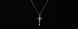Silver crucifix necklace worn on a black sweater.