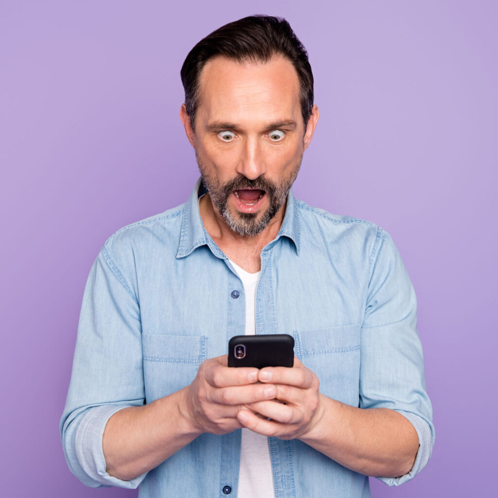 Outraged man gaping at his smart phone